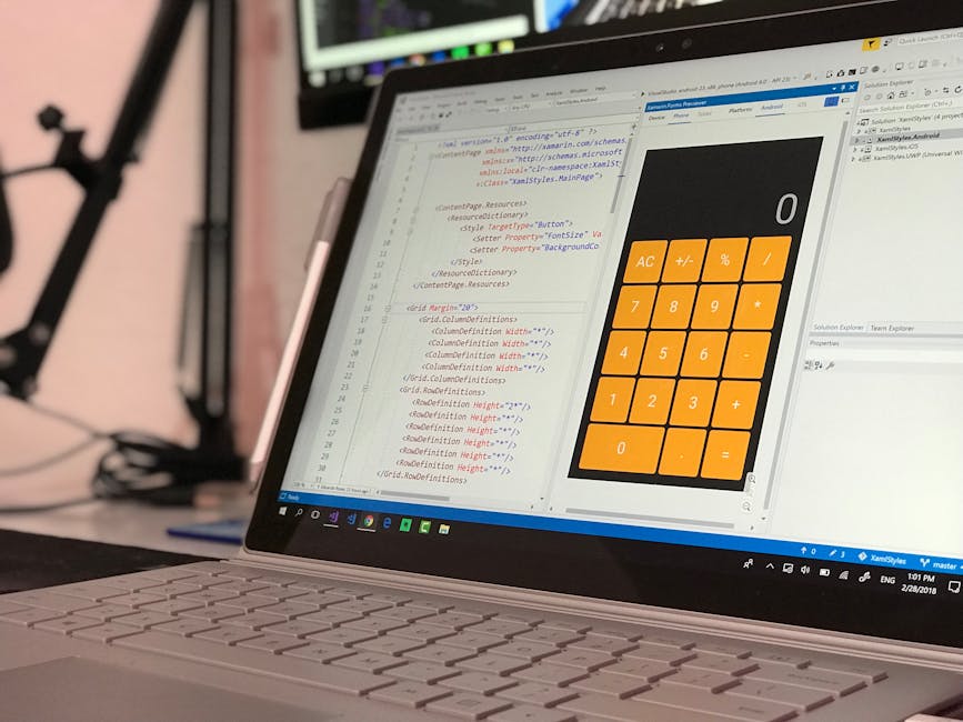 A close-up view of a laptop with a silver keyboard displaying a software interface that includes lines of HTML and CSS code on the screen. To the right of the code, there is a digital calculator with 